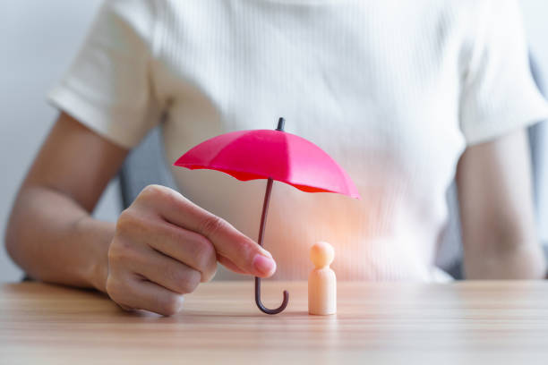 mão segurando guarda-chuva vermelho e homem de madeira da tampa. pessoas protegem, seguro de vida, saúde e liderança conceitos - social insurance - fotografias e filmes do acervo