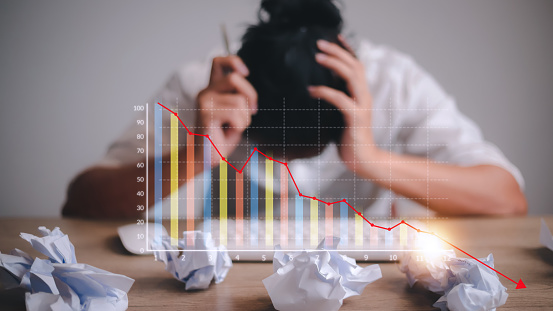 Depressed Businessman Leaning His Head Below a Bad Stock Market Chart