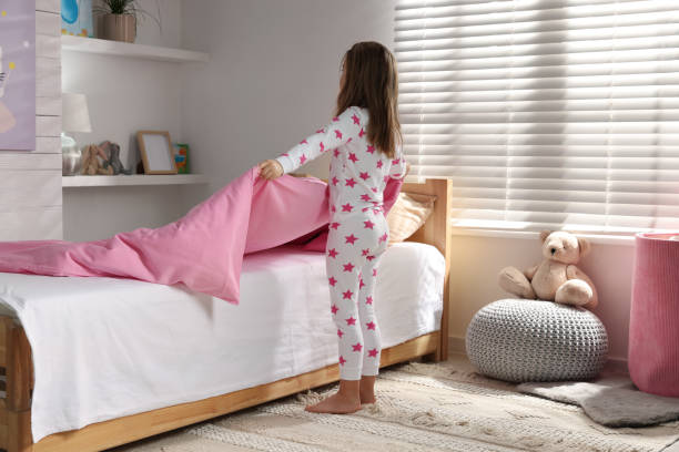 cute little girl making bed at home - material data sheets imagens e fotografias de stock