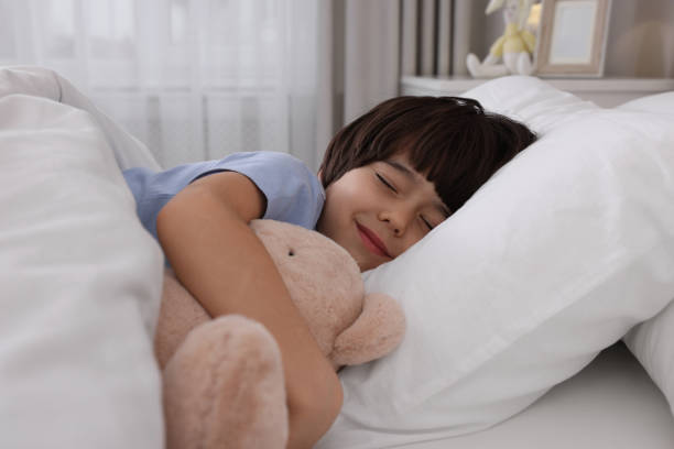 istock Cute little boy with toy bear sleeping in bed at home 1435291692