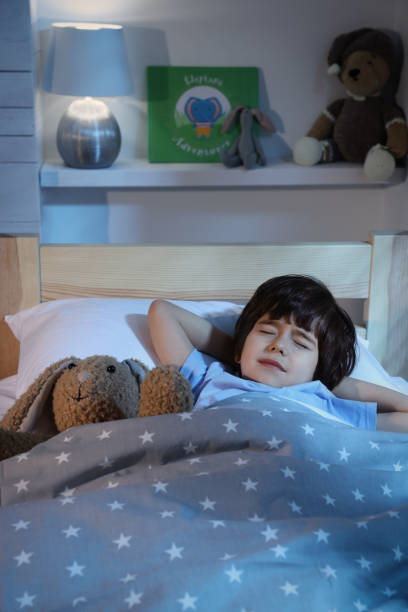 istock Cute little boy with toy bunny sleeping in bed at home 1435291823