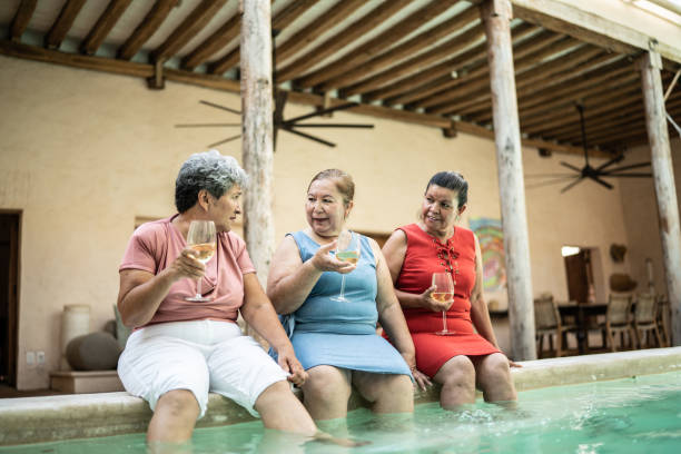 istock Senior friends talking while drinking wine sitting by the pool 1435292453