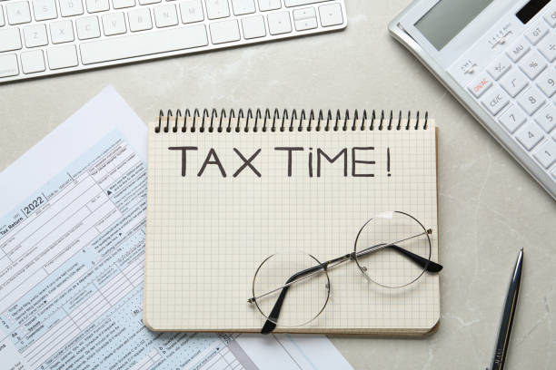 istock Notebook with words Tax Time, documents, keyboard, glasses and calculator on grey table, flat lay 1435294635