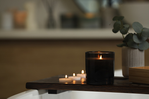 Beautiful burning candles and eucalyptus branches on wooden tray in room, space for text