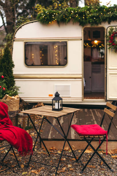 Caravan mobile home with terrace, Mobile home decorated with Christmas decor. Festive atmosphere - lights, red blankets, Christmas trees. Caravan camping. mobile home trailer