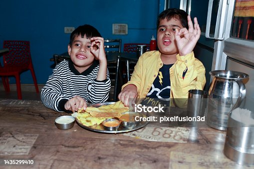 istock Two Children eating Dosa portrait at home 1435299410