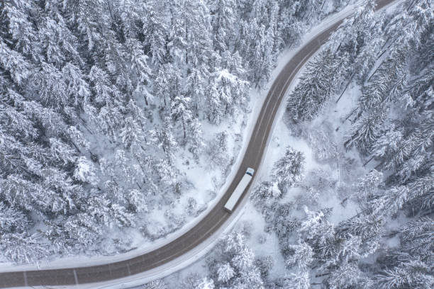 istock Truck Moving During Snowfall on a Winding Curving Mountain Road Passing Thru Snowy Forest 1435301849