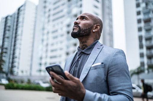 Businessman looking away using mobile phone outdoors