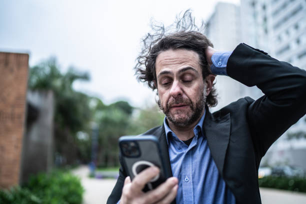 hombre de negocios maduro preocupado usando el teléfono móvil en la calle - dropped call fotografías e imágenes de stock