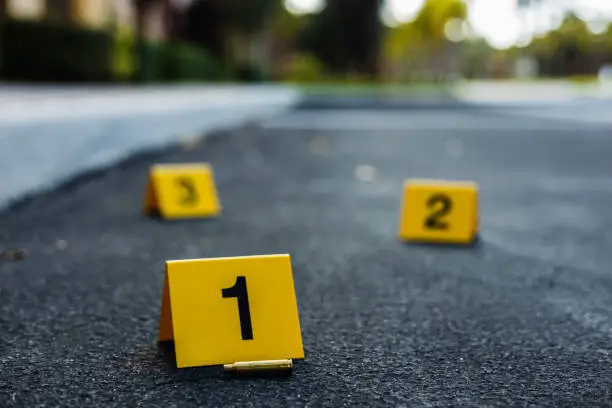 Several crime scene evidence markers and a bullet casing laying next to one of the markers.