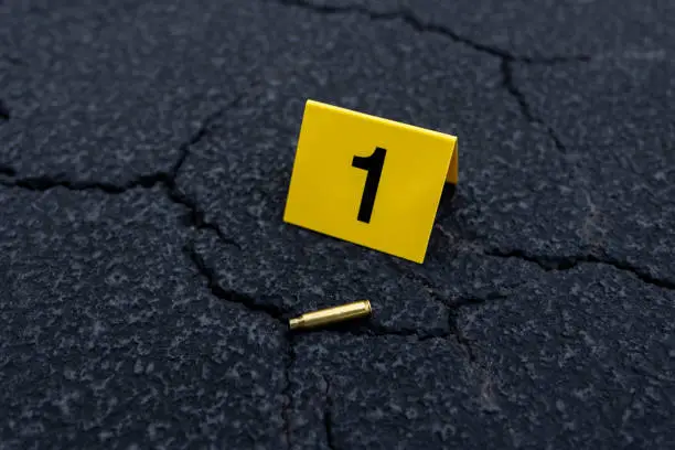 One yellow crime scene evidence marker next to a bullet casing on the street.