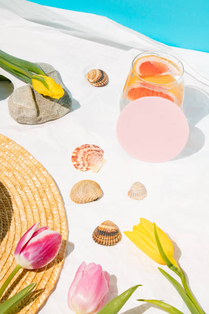 istock Sunny day in the beach. Detox drink with chopped grapefruit. Tulips and shell on light background. Relax time and creative layout. Holiday pattern. Summer minimal concept. Copy space. Top view. 1435304212