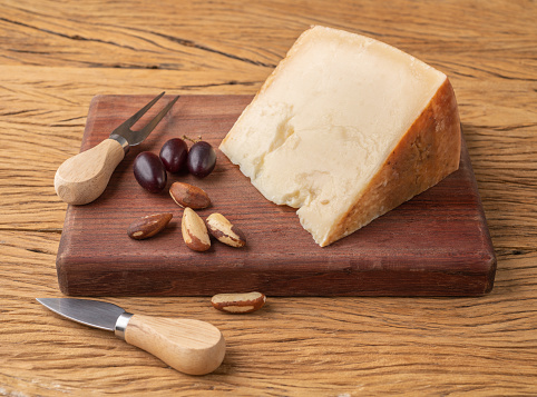 Artisanal Tulha cheese from Brazil with nuts and fruits over wooden table.
