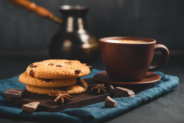 istock Crispy oatmeal cookies with raisins, coffee cup and turkish coffee pot, chocolate chunks on a dark background 1435309486