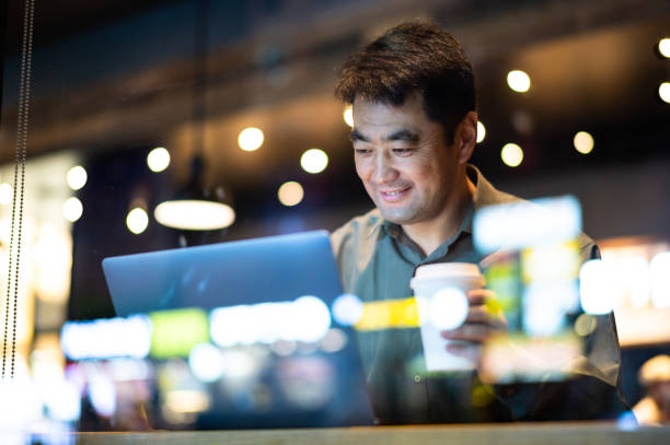 istock Asian middle-aged man using laptop in coffee shop 1435310826