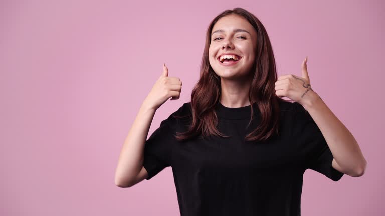 4k video of young woman presenting something over pink background.