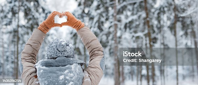 istock woman mittens dressed fashionable gray stands with her back makes heart gesture with her hands against background snowy winter forest 1435316254