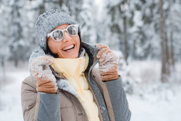 happy woman walking outdoors on a snowy winter day. Female happy cheerful dressed fashionable grey wearing sunglasses happy woman walking outdoors on a snowy winter day. Female happy cheerful dressed fashionable grey wearing sunglasses rejoices in the winter snow-covered forest irish travellers photos stock pictures, royalty-free photos & images