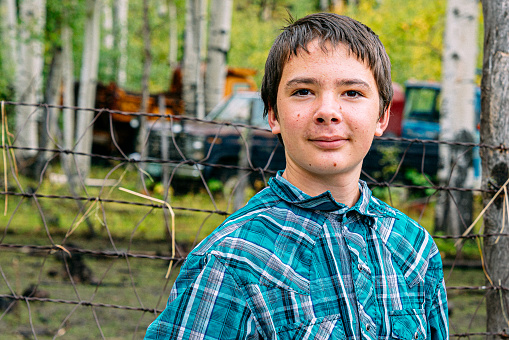Portrait of a Handsome Young Male Caucasian Rancher Teenager Standing and Looking at the Camera on a Small Town Family-Owned Ranch in Colorado, USA