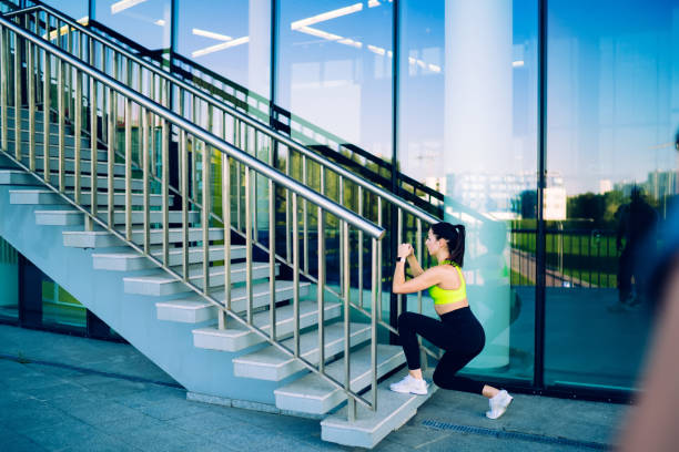 Rear view of young caucasian woman in activewear squatting before starting cardio training keeping healthy lifestyle outdoors, slim female athlete doing exercises for legs on workout slimming vista trasera de una joven caucásica en ropa deportiva en cuclillas antes de comenzar el entrenamiento cardiovascular mantener un estilo de vida saludable al aire libre, atleta delgada haciendo ejercicios para las piernas en el entrenamiento adelgazando