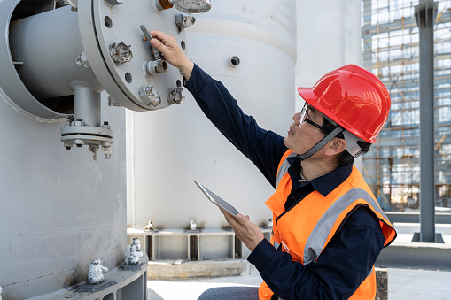 An Asian male engineer is checking the equipment in the chemical plant