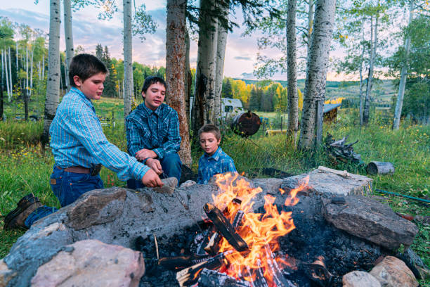istock Young Caucasian Rancher Brothers Sitting Together After Building a Camp Fire in a Firepit in the Back Yard on a Small Town Family-Owned Ranch in Colorado, USA 1435335921