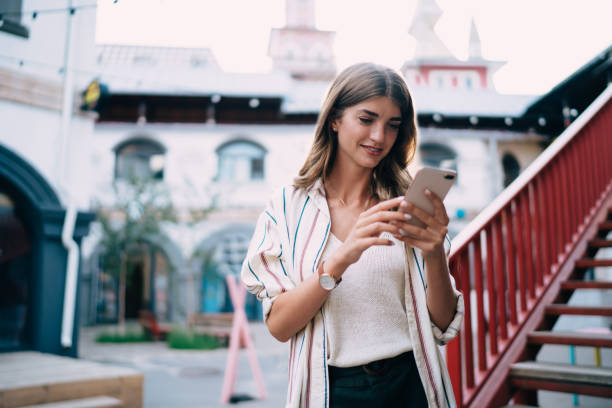 istock Attractive female millennial making mobility booking via cellular application, beautiful hipster girl reading received email message and sending sms answer using 4g smartphone internet in city 1435336415