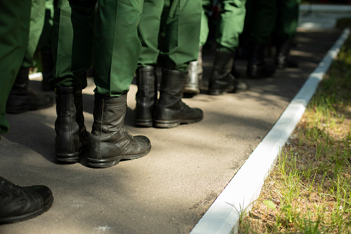Military stands in row. Soldiers' shoes. Boots and military uniforms. Formation of military personnel.