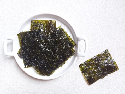 Korean seaweed or nori or gim or kim. is a generic term for a group of edible seaweeds dried to be used as an ingredient in Korean cuisine. Served on white plate. Isolated background in white.