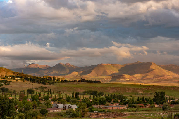 A view of the mountains at sunset in Clarens, South Africa A view of the mountains lit up in gold under a stormy sky at sunset in Clarens, South Africa. This popular tourist destination is near the Golden Gate Highlands National Park in the Free State. golden gate highlands national park stock pictures, royalty-free photos & images
