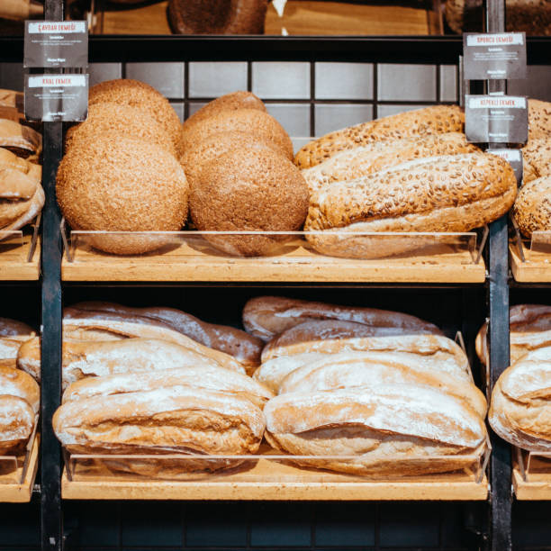 istock Table decorated with various artisan breads produced, Freshly baked handmade sourdough breads, Still life with bread and wheat, Factory for the production of bakery products, breads on the oven counter 1435344015
