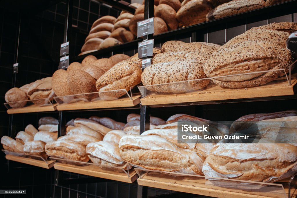 Table decorated with various artisan breads produced, Freshly baked handmade sourdough breads, Still life with bread and wheat, Factory for the production of bakery products, breads on the oven counter Artisanal Food and Drink Stock Photo