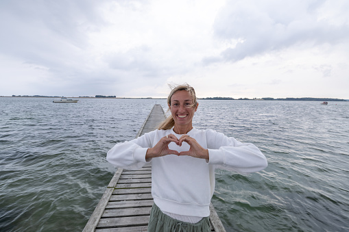 One female on wooden lake pier relaxing and enjoying sea view scenery, travel in Northern Europe concept