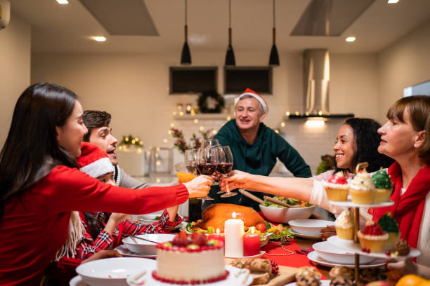 istock Multi-ethnic big family celebrating Christmas party together in house. Attractive diverse people having dinner and toasting a glass of wine to celebrate holiday Thanksgiving, X-mas eve on dining table 1435347312