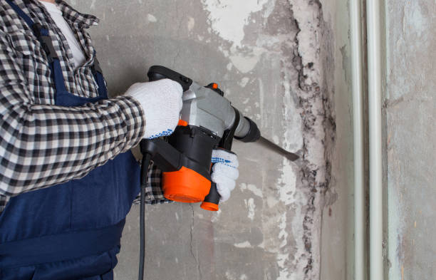 istock The builder with hammer drill perforator equipment making hole in wall at construction site. Repair work, interior decoration of walls. 1435349414
