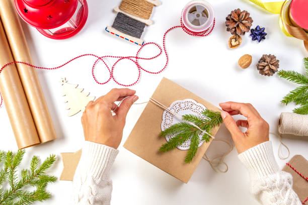 istock Christmas gift wrapping. Woman's hands packing Christmas presents on white table 1435350928