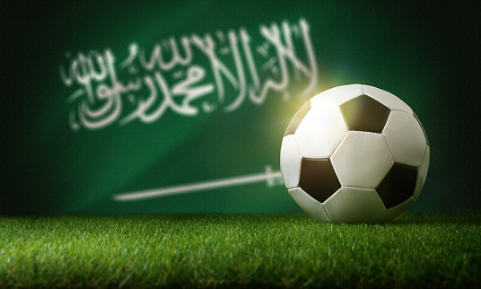 Saudi arabia national team composition with classic ball on grass and flag in the background. Front view.