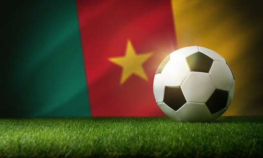 Cameroon national team composition with classic ball on grass and flag in the background. Front view.