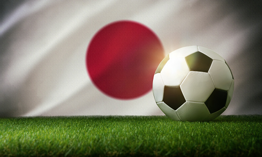 Japan national team composition with classic ball on grass and flag in the background. Front view.
