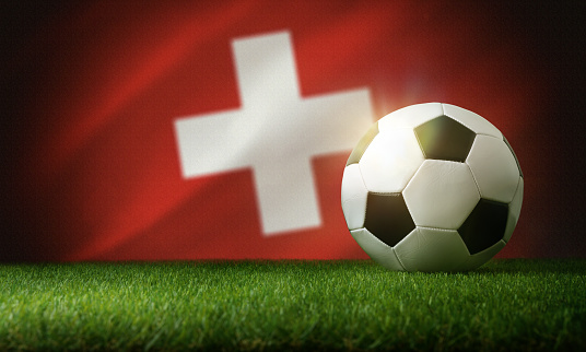 Switzerland national team composition with classic ball on grass and flag in the background. Front view.