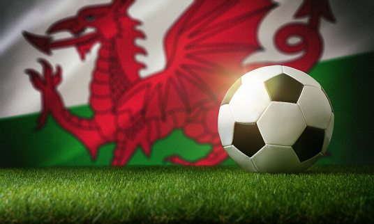 Wales national team composition with classic ball on grass and flag in the background. Front view.