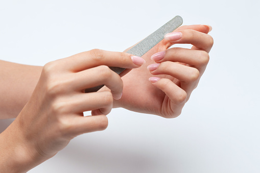 the girl saws with a nail file and shaped her nails during the nail extension procedure in a beauty salon. Professional hand care.
