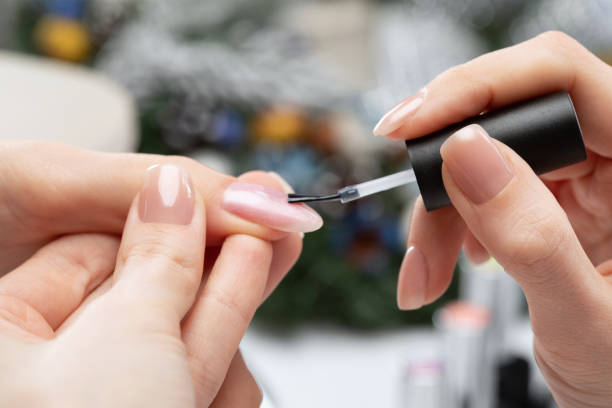 The master of the manicure coats nails with gel polish in the beauty salon. Professional care for hands. New Year concept. stock photo