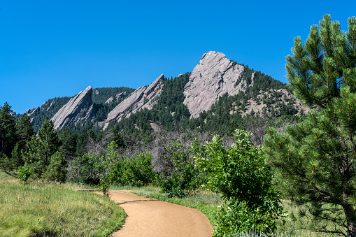 The Flatiron Range near Boulder, Colorado. The image shows a hiking trail leading to the rock formations.