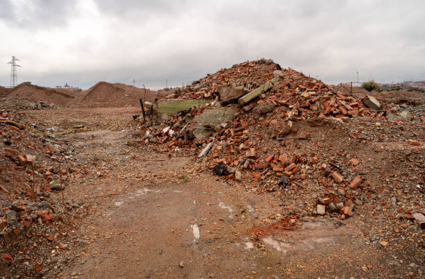 Piles of rubble of brick, stone and concrete. Remains of the destroyed industrial building under lead-colored sky