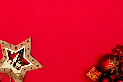 Top view photo christmas tree toys of red colour,christmas star decoration on red background for greeting card. Xmas backdrop with space for text.Copyspace.