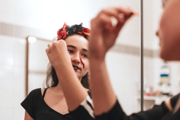 istock girl putting on makeup for halloween 1435364127