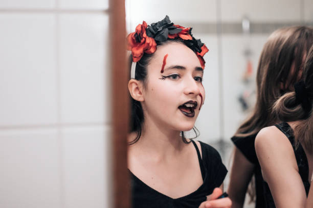 girl in costume with halloween makeup looking herself in mirror, part of series
