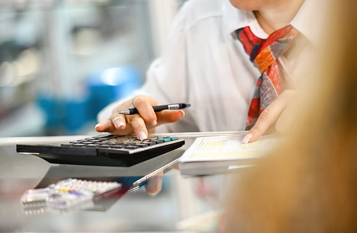 Close-up of saleswoman issuing an invoice, using calculator