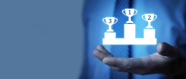 istock Human hand showing winners podium with three winning cups. 1435365758